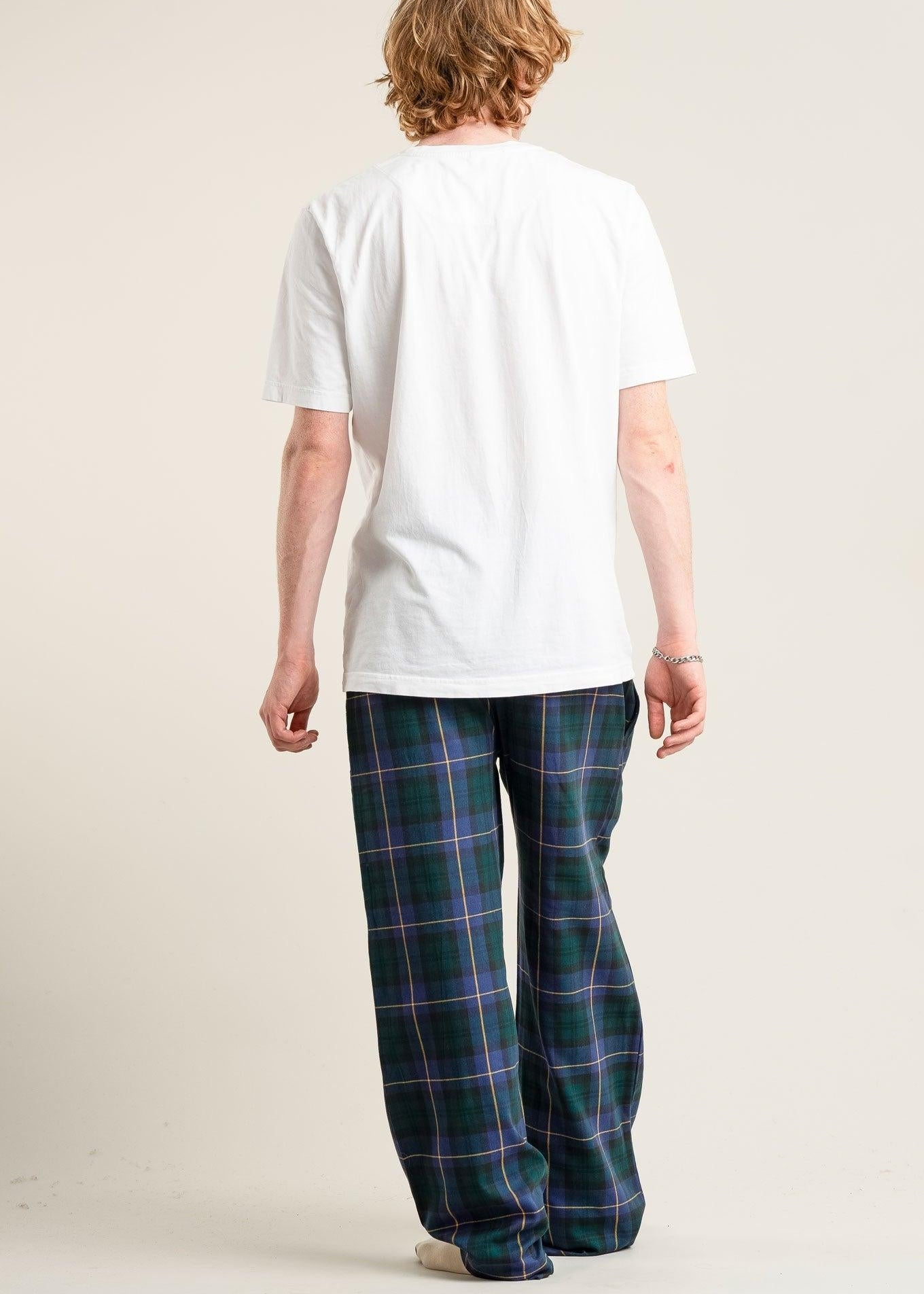 Person wearing a white t-shirt and plaid pants on a plain background