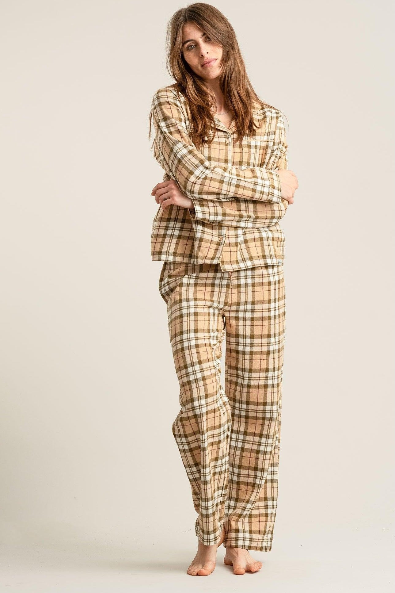 Woman wearing a plaid pajama set on a plain background