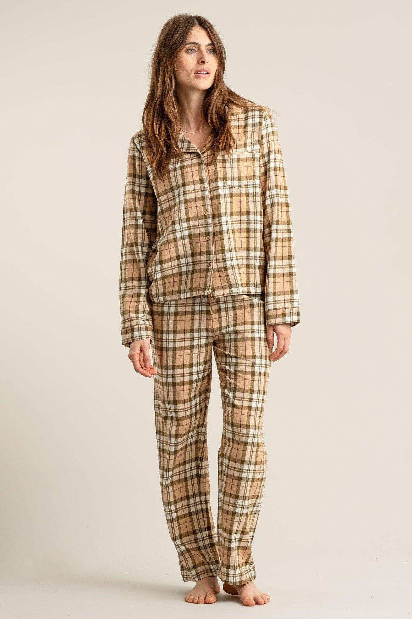 Woman wearing a plaid pajama set on a beige background