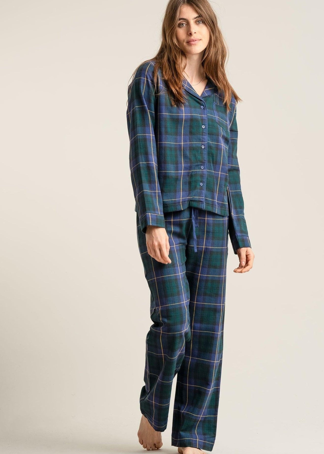 Woman wearing green plaid pajamas on a plain background