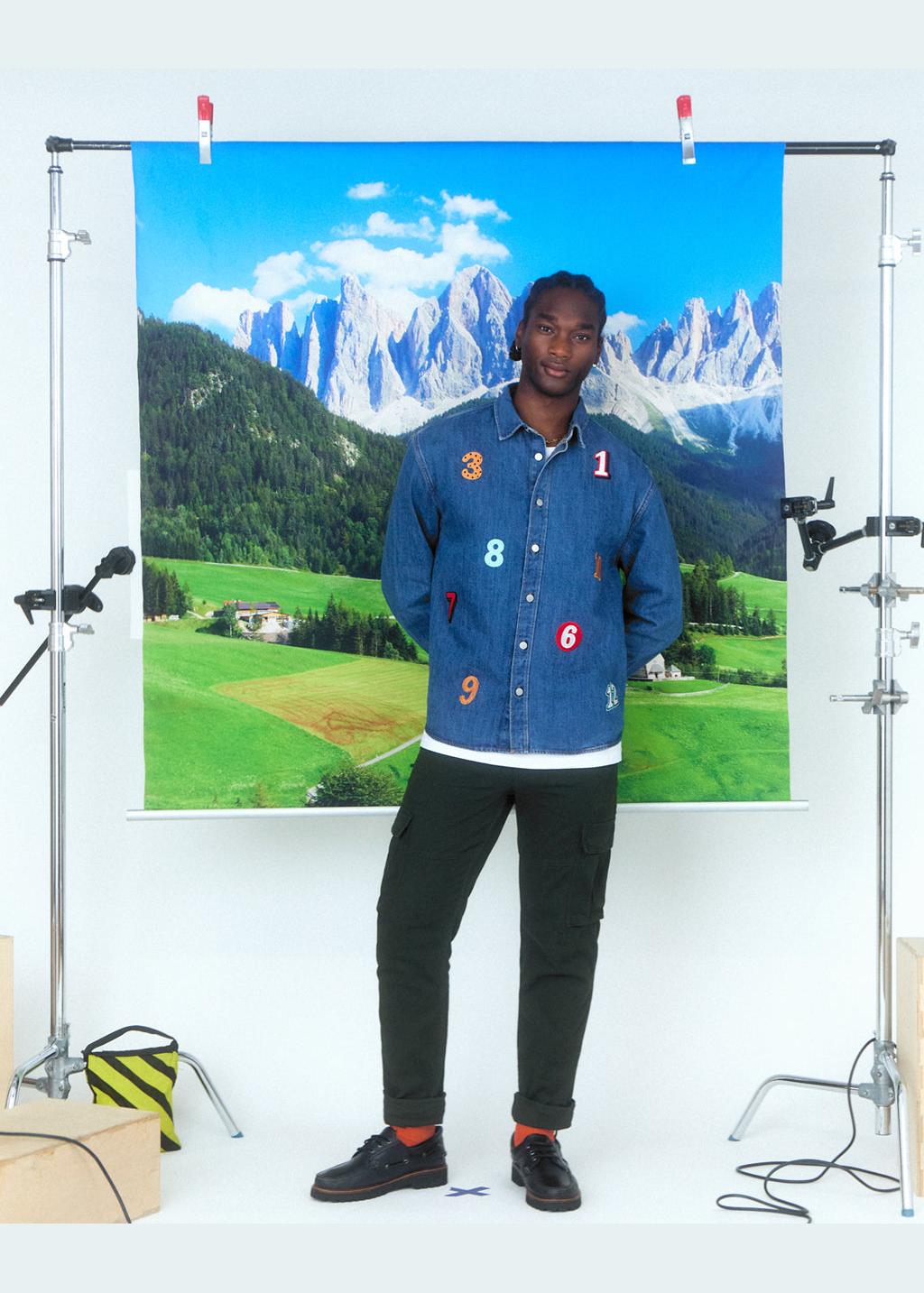 A man wearing a denim shirt with numbers embroidered 