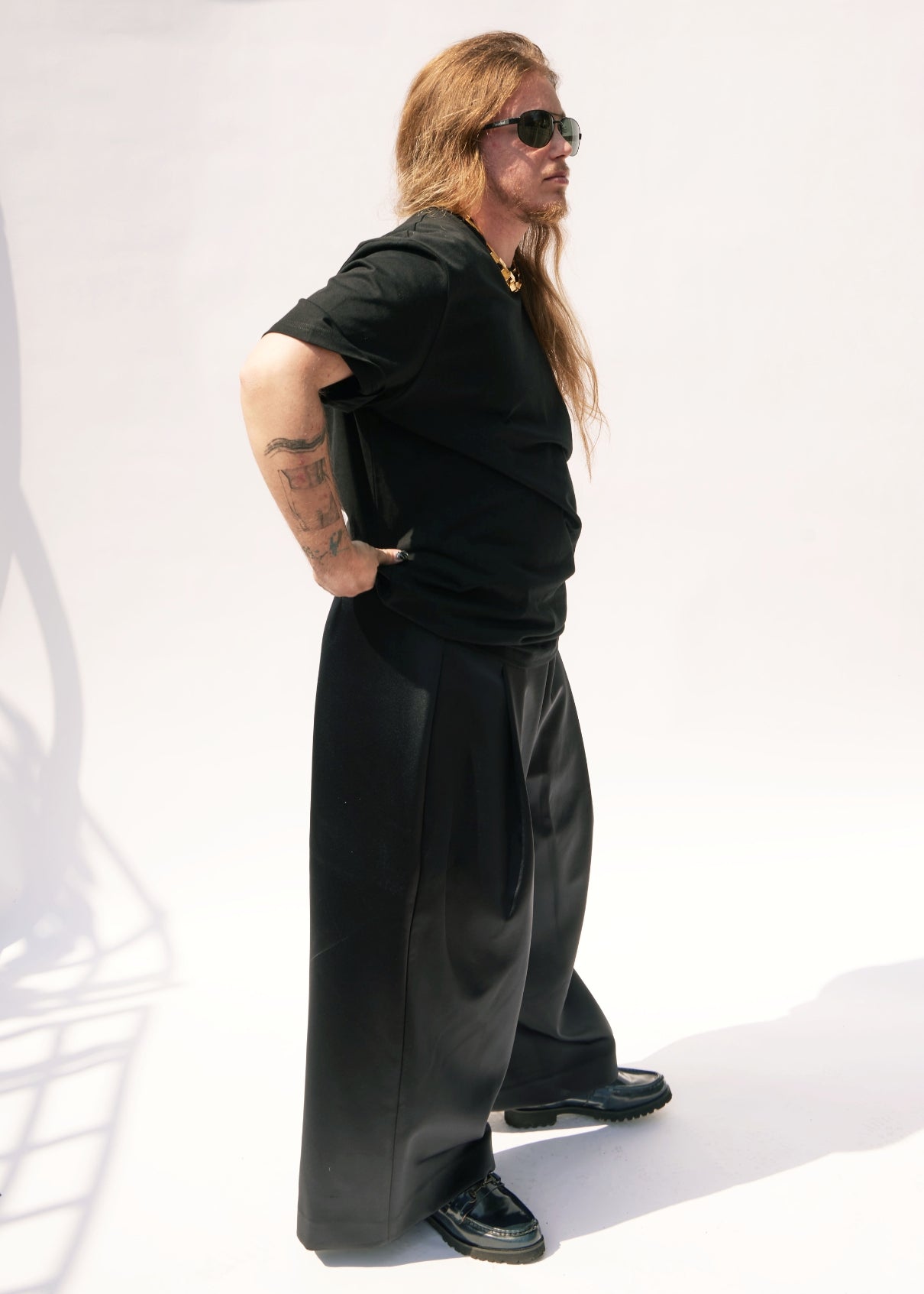 Person wearing a black outfit with sunglasses on a white background