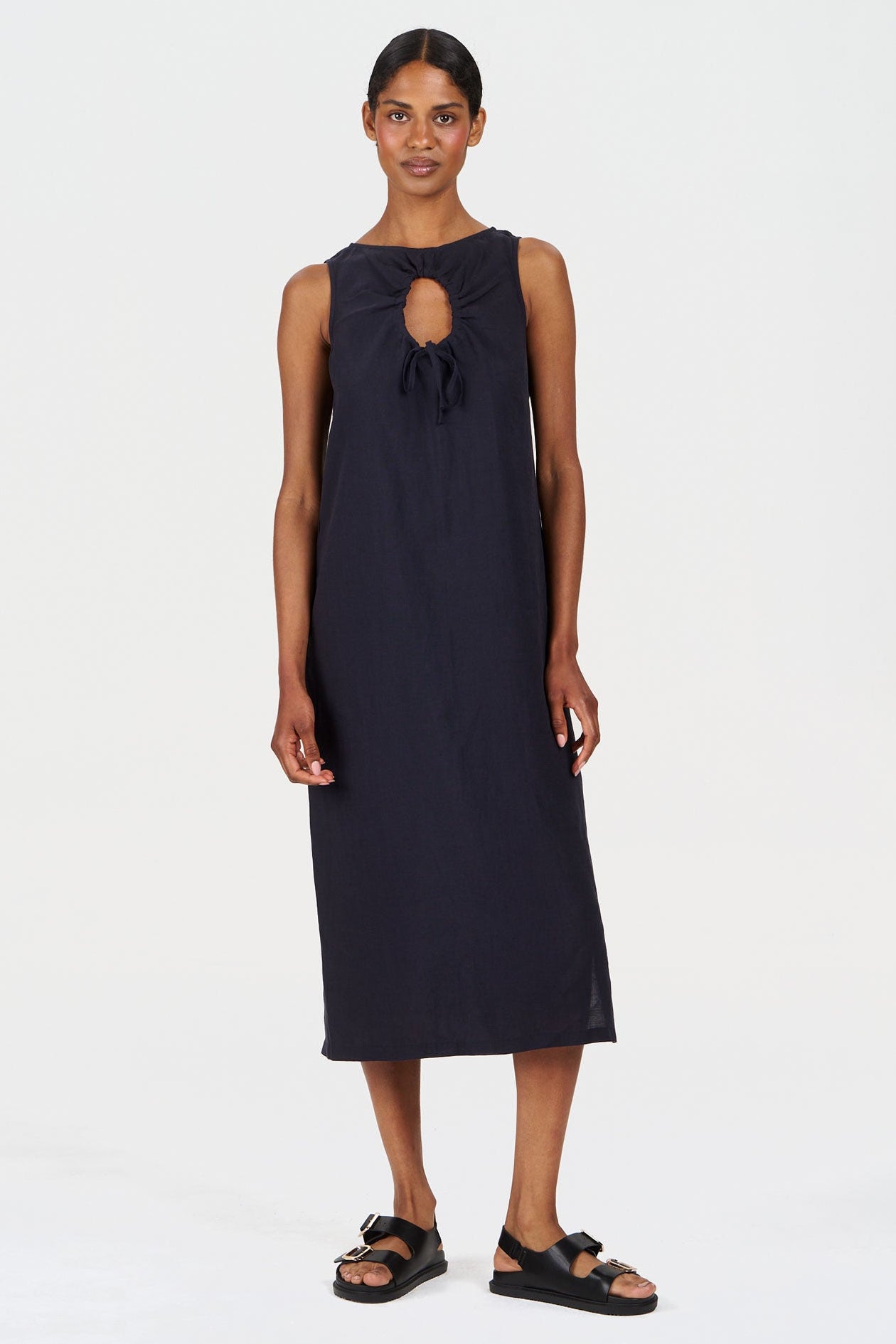 Woman wearing a black sleeveless dress with a cutout design on a white background