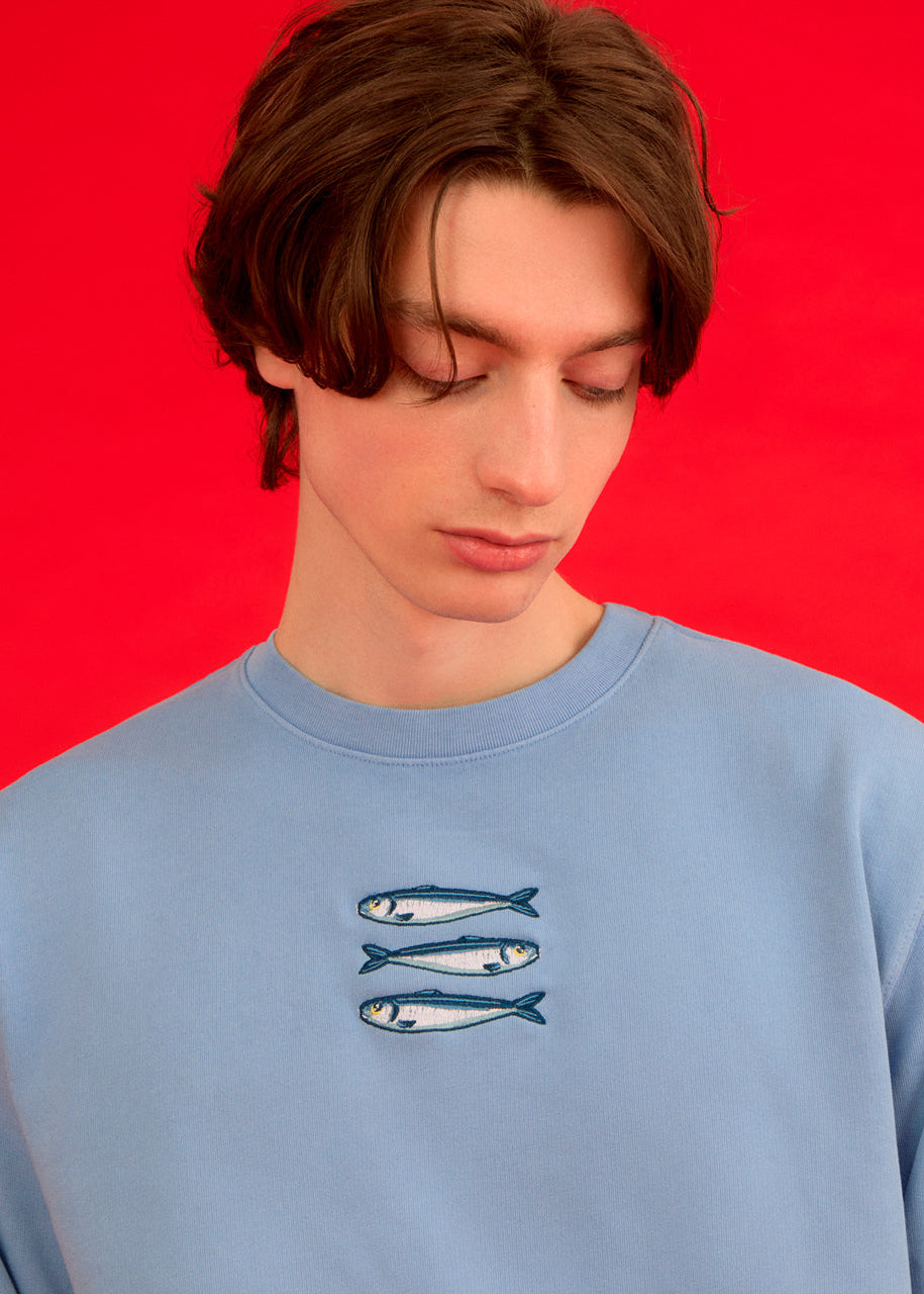 a man wearing a blue ingmarson sweatshirt with sardines embroidered 