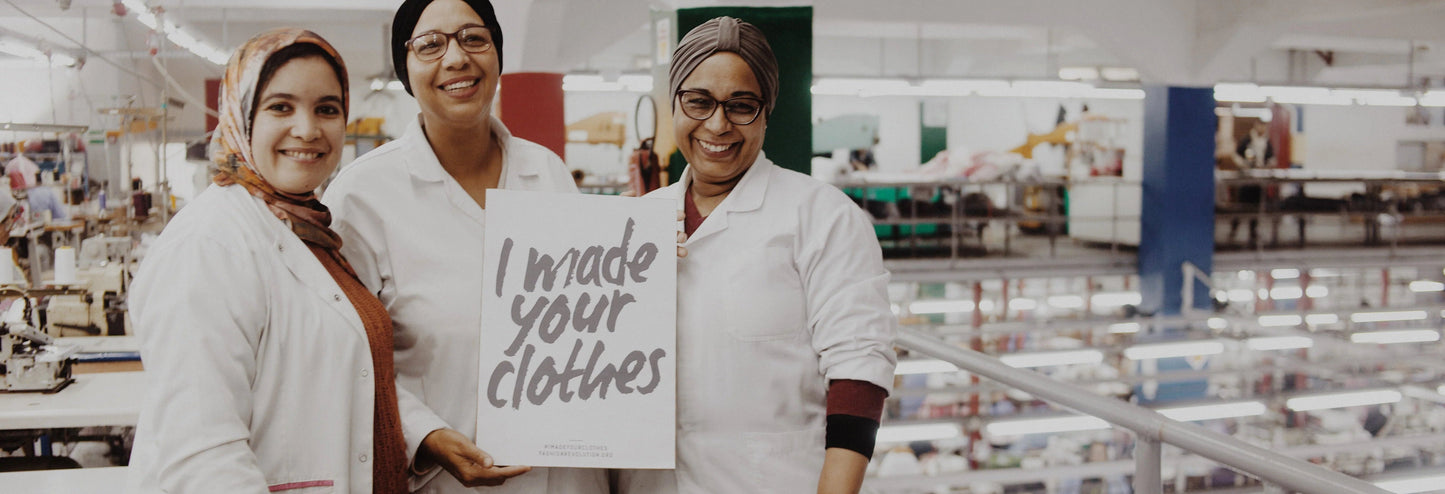 Three people in a factory setting holding a sign that reads 'I made your clothes'.