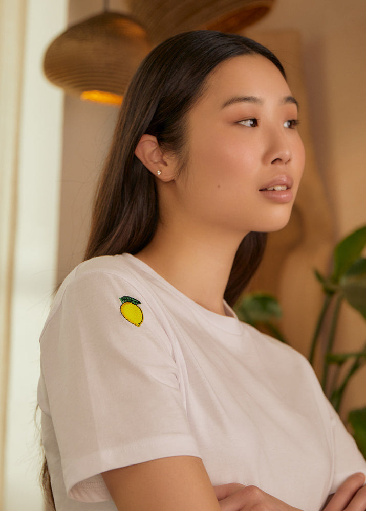 
                  
                    a woman wearing a white t-shirt with lemons embroidered 
                  
                